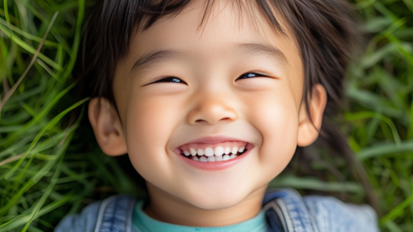 mediamice_smiling_Asian_child_laying_down_on_green_grass_54a3de12 dd88 412c b48d e5974057c1a8 topaz face upscale 4x